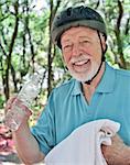 A senior man taking a break from exercise to towel off and have a drink of water.