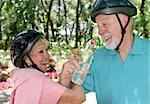 An attractive senior couple joking with eachother as they take a water break during a bike ride.