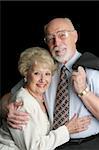 An attractive, affectionate senior couple on a black background.