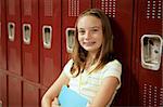 An adorable teen girl with braces and freckles standing in front of her locker.