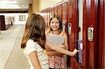 Middle school girls gossiping at their lockers.