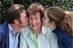 A pretty grandmother receiving kisses from her family and smiling.