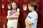 A boy and a girl in school, chatting by their lockers.