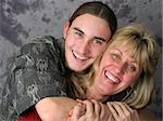 A happy mother and teen son laughing and embracing.