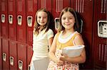 Two adolescent school girls in front of their lockers.