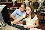 A girl and a boy student doing research together in the computer lab at school.