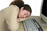 A teen girl fast asleep by the computer, worn out from studying.