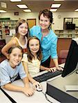 A helpful teacher instructing her students on the computer.  Focus on teacher.