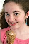 A cute teen girl with freckles and braces, holding a chocolate ice cream cone.