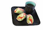 Colorful Japanese salad rolls and tea, served in on black and isolated on a white background. (matte texture of plate and cup may resemble artifacts)