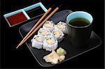 A complete sushi meal with tea on black.