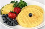 Golden waffles served with blueberries, strawberry and pineapple.