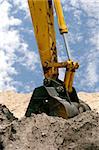 A back hoe digging in piles of dirt