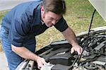 An auto mechanic checking the engine of a car. Horizontal.