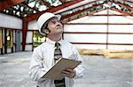 A building inspector examining the the steel girders in a building under construction.  Horizontal view.