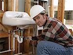 A plumber installing fixtures in a construction site.