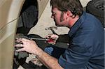 An auto mechanic inspecting the brake housing on a car.