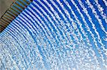 Abstract of lines of cascading water, with a blue sky background.