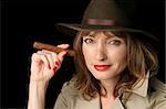 A beautiful, sexy woman in a trenchcoat and fedora hat holding a cigar.