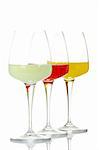 Three glasses with beverages, reflected on white background. Shallow DOF