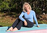 A beautiful, mature woman relaxing after doing yoga outdoors.