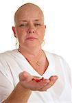 A medical patient holding a handful of pills and looking like she doesn't want to take them.