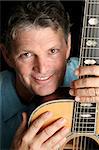 A handsome, mature musician posing with his guitar.