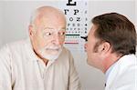 Optician using and ophthalmoscope to look into a patient's eyes.