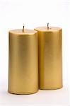 Two Gold candles against a white background