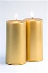 Two Gold candles against a white background