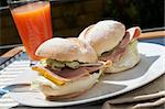 Ham and cheese sandwich on portuguese rolls served with juice on the sunny day