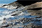 Years of oil residue glisten in the morning sun on wet rocks at Hazard Rock in Narragansett, RI