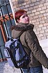 Image of a redheaded girl student with a backpack in front of the University building.Shot with Canon 70-200mm f/2.8L IS USM