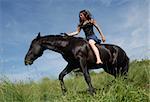 young teenager and her black horse in training of jumping competition