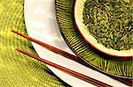 Asian chopsticks, bowls filled with herbs and green mat