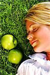 Young girl lying in the grass with  apples