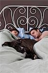 Jeune couple endormi dans son lit avec chien
