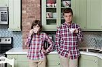 Young couple holding teacups in kitchen