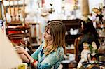 Femme inspecter les articles en vente dans le magasin d'antiquités