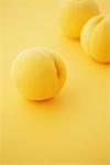 Close Up Of Three Golden Peaches On Yellow Background