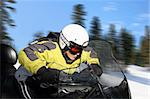 A young man riding a snowmobile