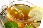 Lemon balm tea in a glass cup with garnish on light background