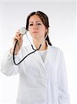 cute brunette in white medical gown   and a stethoscope focus on the stethoscope