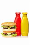 Double cheeseburger with mustard and ketchup bottles, reflected on white background. Shallow DOF