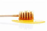 Honey and wooden drizzler, reflected on white background