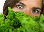 Beautiful young woman portrait holding a healthy lettuce in front of the face