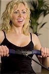 A beautiful young blond woman working out on a rowing machine at the gym