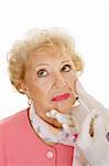 Senior woman getting cosmetic injections in the wrinkles around her mouth.  White background.