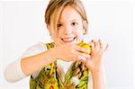 Studio portrait of a young blond girl who is presenting her painted easter egg