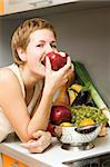 Beautiful girl eating fresh fruits at the kitchen